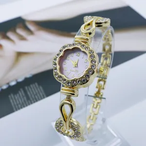 Vista en detalle del elegante reloj de cuarzo para mujer dorado con flor de pedrería.