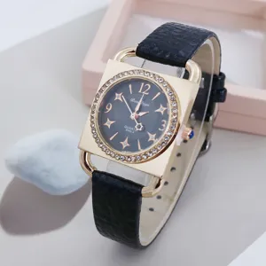 Square quartz watch detail, gold rhinestone case and black leather strap for women.