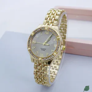 Dettaglio orologio al quarzo con strass dorati, cinturino in maglia e quadrante decorato.