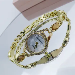 Montre quartz femme strass dorée détail, élégant bijou bracelet mode avec des pierres marron.