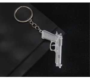Detailed shot of a silver metal pistol keychain, exquisite gun model pendant for keys and bags.