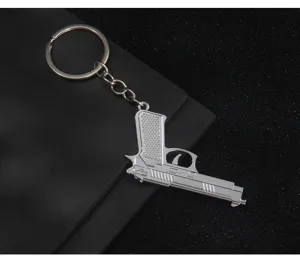 Close-up of silver metal pistol gun keychain, detailed model pendant keyring accessory.
