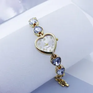Close-up detail of the gold-toned heart-shaped quartz watch featuring sparkling crystal links.