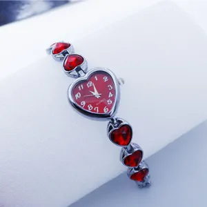 Close-up detail of a red heart crystal quartz watch with metal chain strap for women.