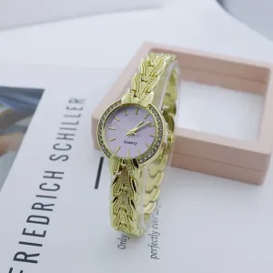 Detail view of a luxury gold-tone quartz wristwatch featuring a purple dial and rhinestone bezel.