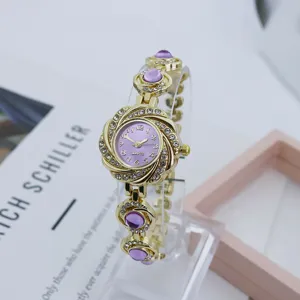 Damen Gold Quarz Uhr mit lila Blumen Strass Zifferblatt und lila Edelsteinen am Armband.