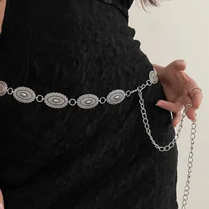 Gros plan détail de chaîne de taille argentée vintage avec des breloques ovales gravées.