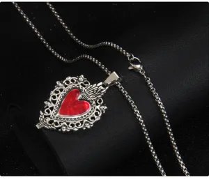 Détail de collier pendentif cœur rouge sombre gothique, chaîne en acier vintage.