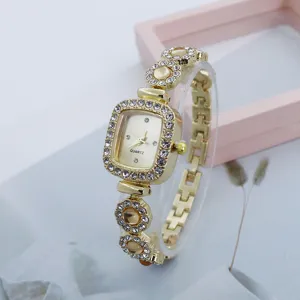Close-up shot of a luxurious gold quartz square rhinestone watch with sparkling crystals.