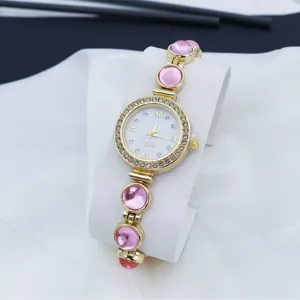 Dames quartz horloge met roze edelstenen en strass, elegant gouden mode detail.