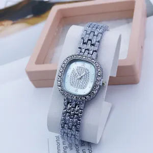 Detail view of luxury rhinestone square quartz watch with silver metal strap for women fashion.