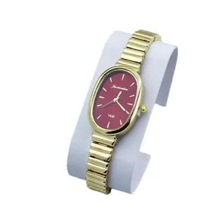 Elegante reloj de cuarzo para mujer con esfera roja ovalada y pulsera metálica dorada.