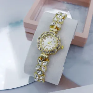 Close-up detail of luxury gold-tone rhinestone quartz watch with floral butterfly link bracelet.