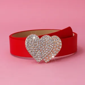Gros plan sur la boucle double cœur en strass étincelante sur une ceinture en cuir rouge.