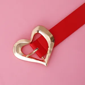 Détail de ceinture en cuir PU rouge avec boucle dorée en forme de cœur sur fond rose.