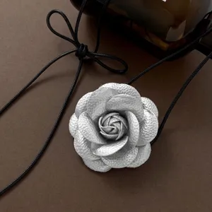 Silbernes Leder-Kamelienblüten-Anhängerdetail, feine Textur Nahaufnahme der schwarzen Kordel.