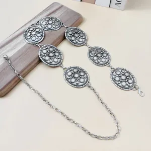 Vue détail de chaîne de taille femme argentée vintage avec plaques ovales sculptées.