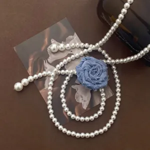 Perl-Taillenkette Detail mit zarter blauer Stoffrose und elegantem modischen Design.