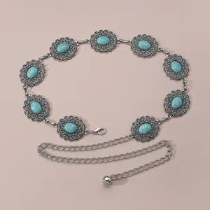 Gros plan détaillé sur une ceinture de taille en métal argenté vintage avec pierres turquoise.