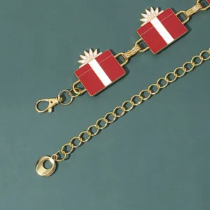 Exquisita correa de cadena dorada con dijes esmaltados de caja de regalo roja y blanca.