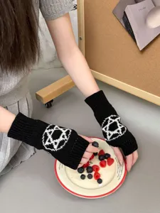 Dettaglio di guanti senza dita in maglia con pentagramma nero e bianco per look Lolita.