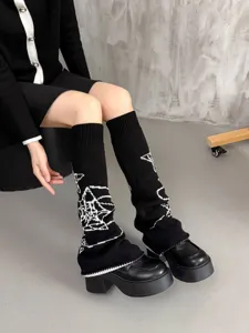 Detailaufnahme schwarzer Strickbeinlinge mit weißen Sternmotiven und coolen Plateauschuhen.