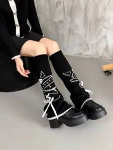 Black gothic knit leg warmers featuring white skull patterns and elegant velvet bow details.
