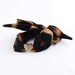 Dettaglio di tessuto leopardato e cuore in strass, elegante accessorio di gioielleria moda DIY.