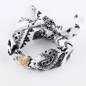 Vista dettagliata della fascia paisley in bianco e nero con ciondolo a cuore in strass.