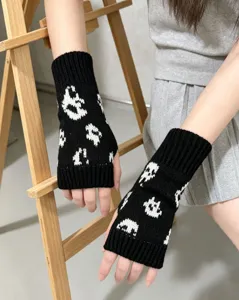 Gros plan sur des gants en tricot noir et blanc sans doigts avec motif de fantôme mignon.