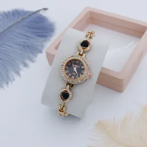 Detailfoto van een luxe dames quartz horloge met sprankelende strass stenen en hart armband.