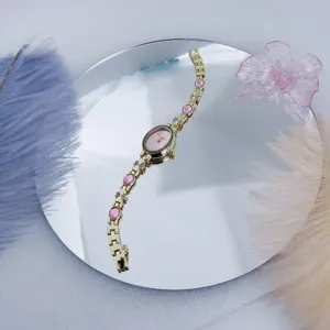 Lujoso reloj de cuarzo dorado para mujer con piedras ovaladas rosas y esfera delicada.