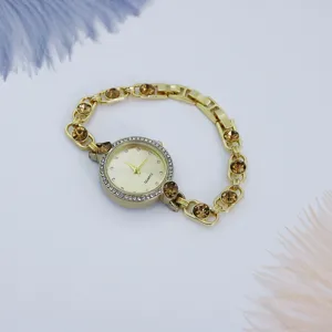 Detalle de reloj de cuarzo para mujer elegante con pulsera de cadena dorada y cristales.