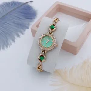 Gedetailleerd overzicht dames luxe quartz horloge met groene hart armband en strass bezel.