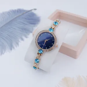 Vista detallada de reloj de cuarzo para mujer con esfera azul, bisel de estrás y correa de cristal.