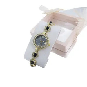 Elegante goudkleurige dames quartz horloge met strass rand en zwarte steen armband.