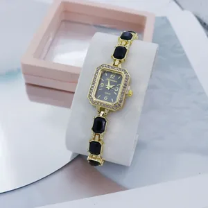 Detailansicht der goldenen Quarzuhr mit quadratischem Strass-Zifferblatt und schwarzen Edelsteinen.
