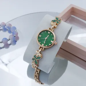Detailweergave van dames kwartshorloge met groene wijzerplaat en vlinder kristallen armband.