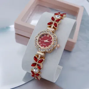 Women's gold-tone floral rhinestone quartz watch with chain bracelet on display.