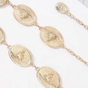 Détail de chaîne de taille en métal doré avec élégants pendentifs ovales tête de taureau.
