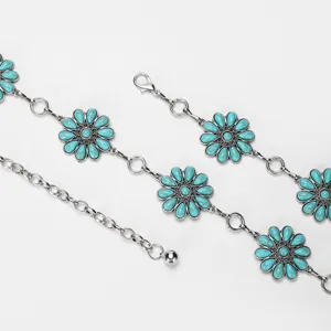 Gros plan détail de chaîne de taille en métal argenté avec breloques tournesol turquoise.