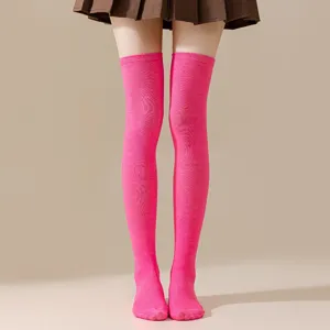 Nahaufnahme Detail von leuchtend rosa Overknee-Strümpfen kombiniert mit einem braunen Rock.