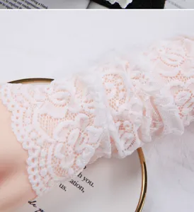 Detailaufnahme von weißen Armstulpen aus zarter Spitzen, mit feinem Blumenmuster-Design.
