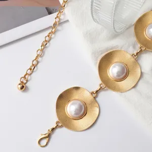 Gouden metalen taillekettinkje detail met cirkelvormige schijven en mooie parels.