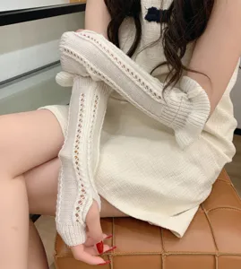 Close-up detail shot of white knitted hollow-out long arm sleeves with delicate ruffle cuffs.