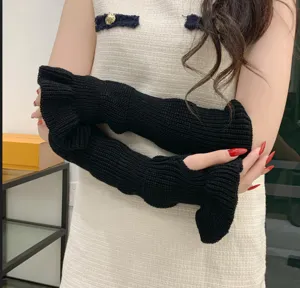 Close-up detail of black knitted arm warmers featuring chic wave ruffles, perfect for winter style.