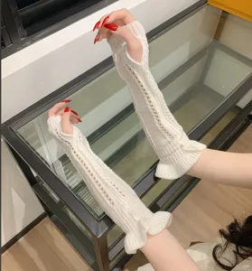 Detailed view of white knit hollow-out long gloves with ruffle cuffs for stylish wear.