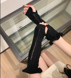 Detail view of black knitted long arm warmers with hollow-out design and ruffle cuffs.