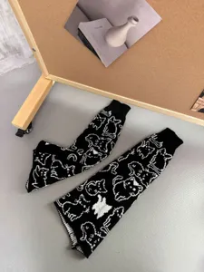 Detailed view of black knit cat pattern leg warmers showing soft texture and cozy winter style.