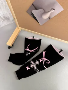 Schwarze Strick-Beinwärmer Detail mit rosa Schleifen und gotischem Kreuzmuster für den Winter.